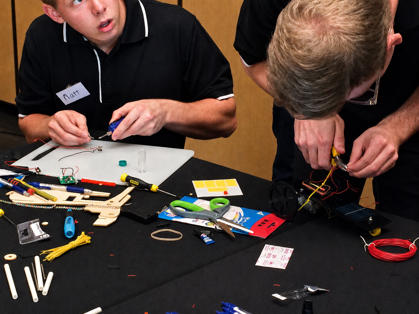 Two participants wiring and assembling their team's scale race car